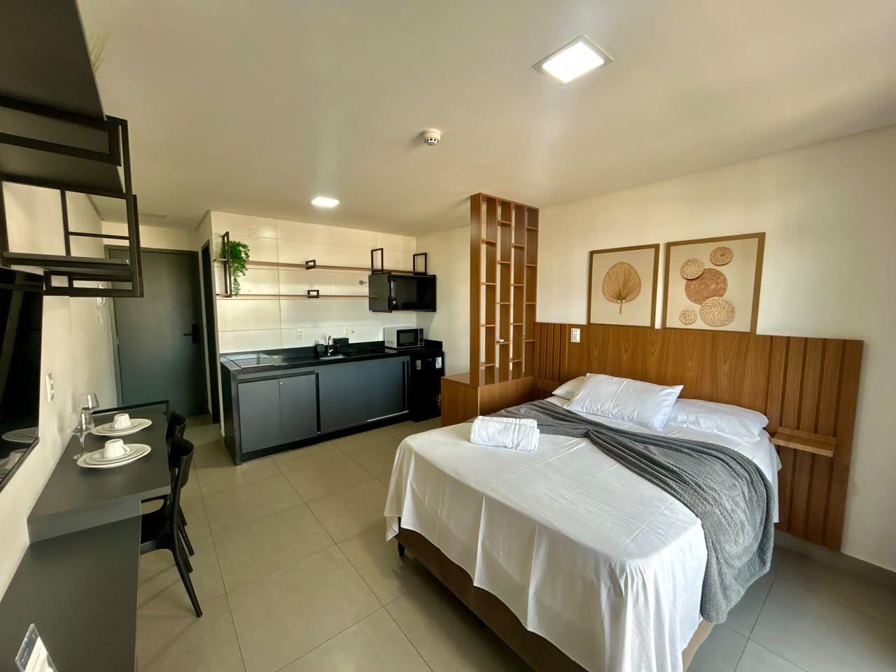 Interior do flat 302 mobiliado, cama de casal, cozinha compacta e área de refeição