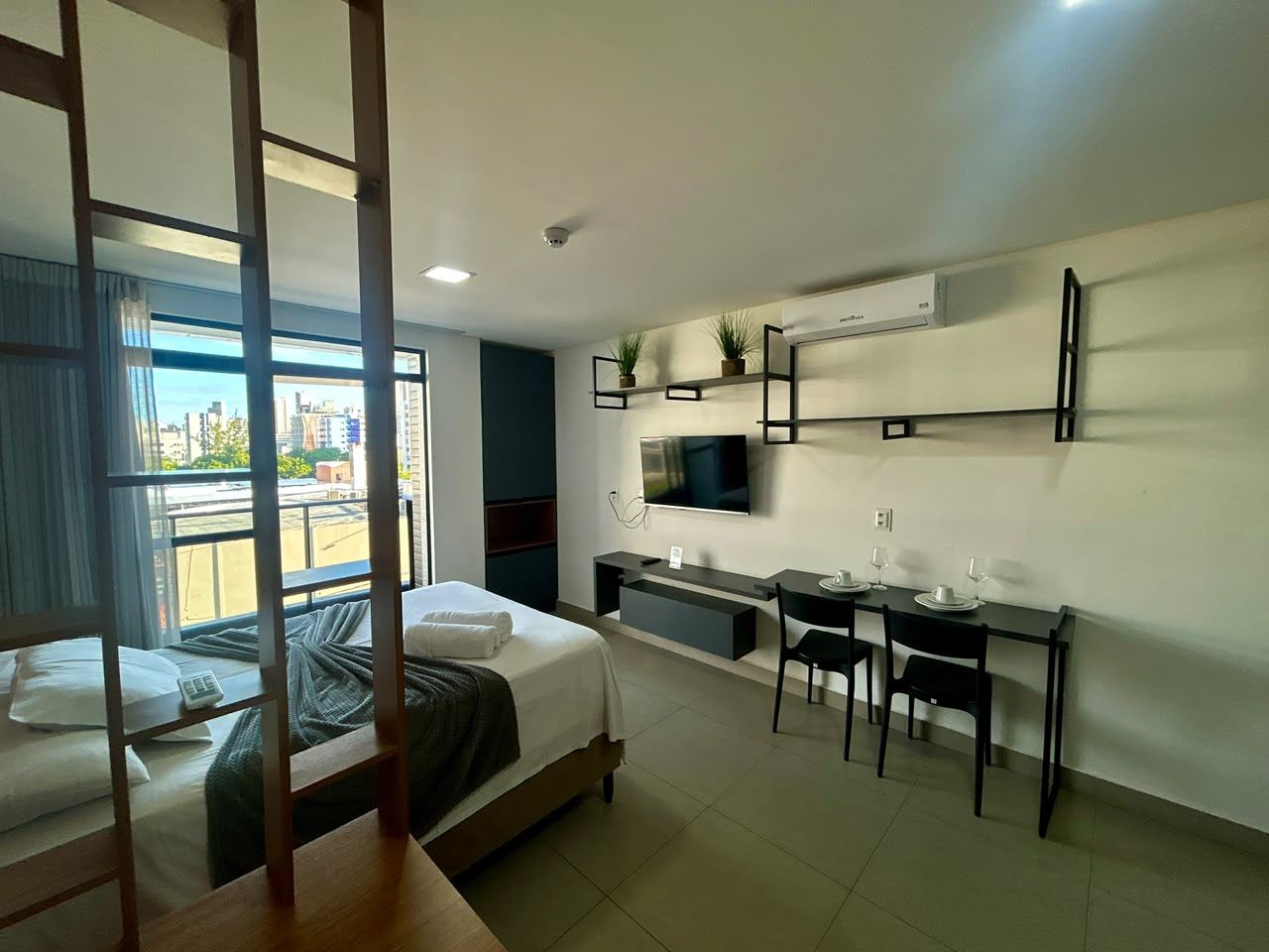 Flat 302 com TV, mesa de trabalho e porta da varanda