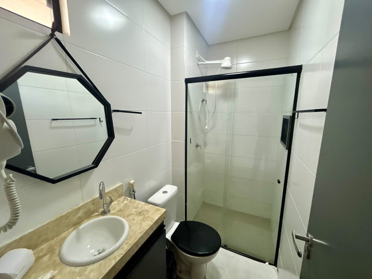 Banheiro do flat 302 com box de vidro, bancada e espelho